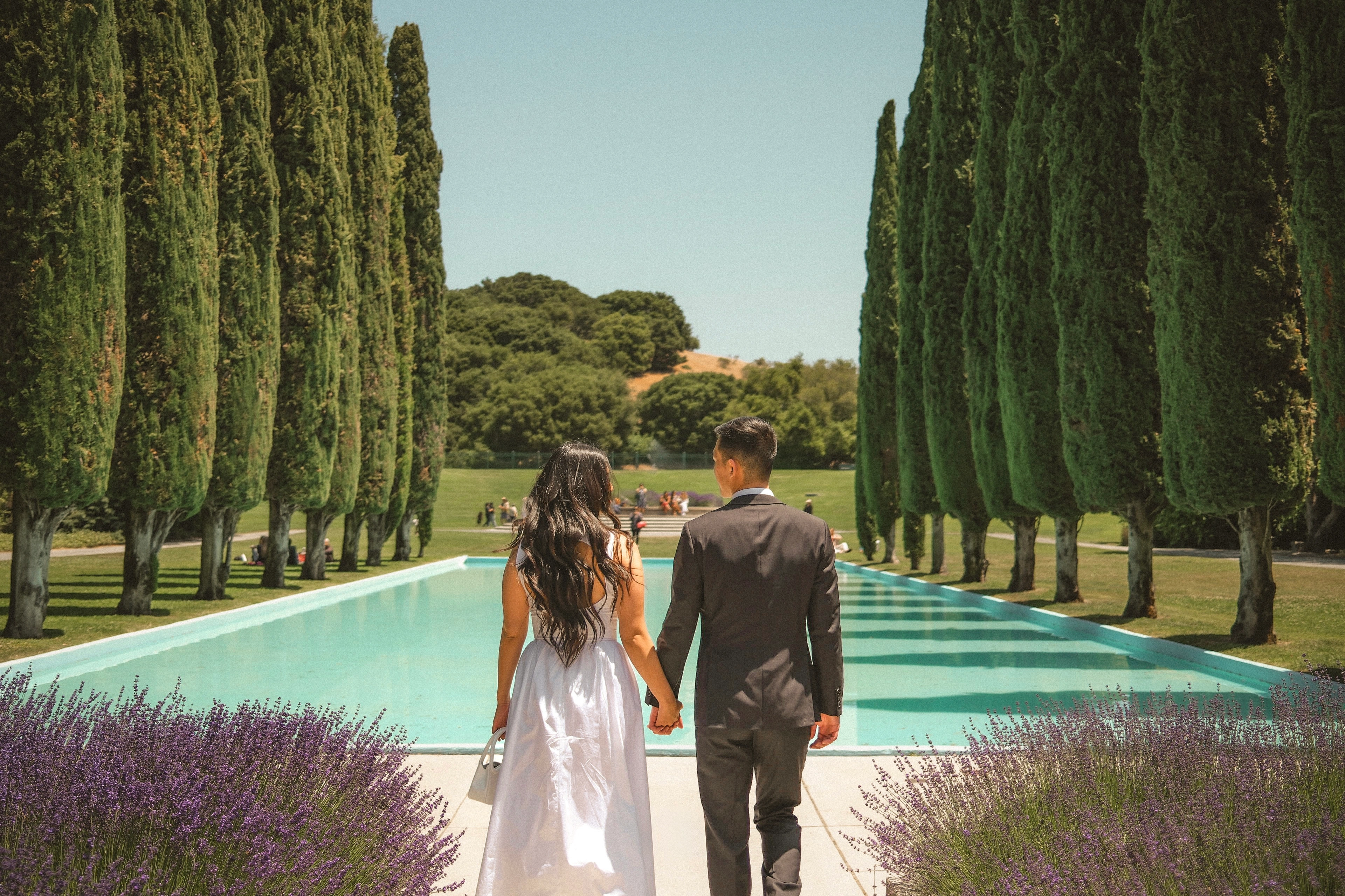 Couple walking by pool with cypress+trees